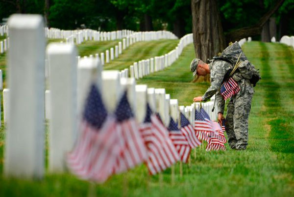 A soldier placing flags at veteran grave site