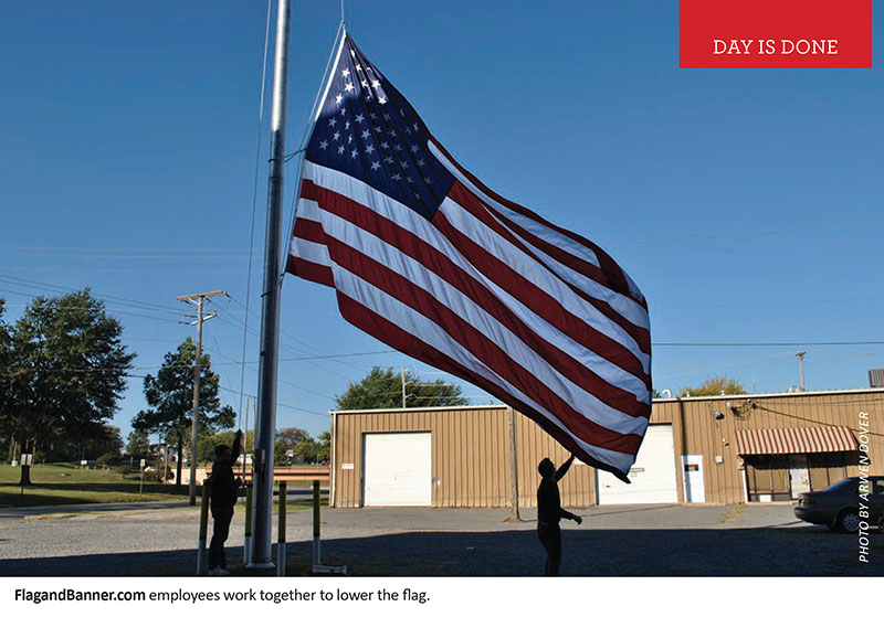 FlagandBanner.com employees work together to lower the flag