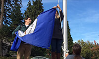 Many Nations Chemawa boarding school students change one of the nine flags at the EMU amphitheater during the Indigenous Solidarity Day ceremony on Oct. 9, 2017. (Emily Harris/Emerald)