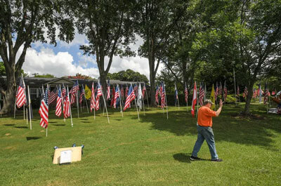 David Rankin, right, of Anderson, a U.S. Army Vietnam Veteran, waves at a motorist passing by his 115 flags on display in his front yard before the Fourth of July in Anderson June 2021. Ken Ruinard / Anderson Independent Mail