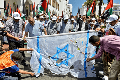 Protesters tear at a makeshift Israeli flag during a protest in the Moroccan capital Rabat on June 23, 2019, against the US-led economic conference in Bahrain with its declared aim of achieving Palestinian prosperity. (AFP)