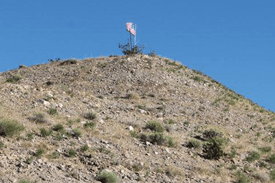 A lone American flag stands atop a mountain peak along Highway 95, JoANN SMITH, News West