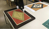 Julienne Crawford, curator at the Arkansas State Archives, talks about the repairs that conservators will make to two early Arkansas state flags, including the original state flag on the left that dates to 1913. - Photo by Staton Breidenthal