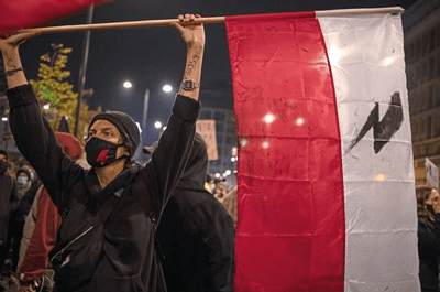 A demonstrator, with the phone number of a legal councilor written on their arm, holds the Polish flag during a Nov. 18 protest against a top court ruling restricting abortions in Warsaw, Poland. (Image source AP)