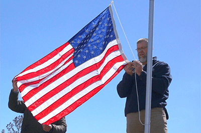 Jamie Popwell, right, attaches an American flag to a new flagpole he put up on Wednesday along Lee Road 721 in Beauregard. Kara Coleman Fields/kcoleman@oanow.com